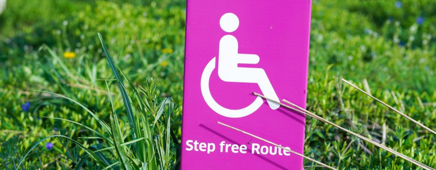 Pink sign on grass saying Step Free Route with wheelchair image