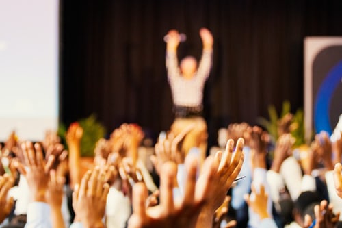 Blurred image of audience with raised hands