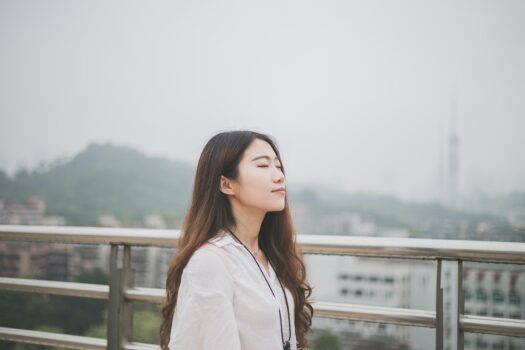 Long brown haired girl by a bridge with her eyes closed