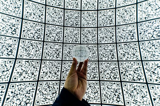 Person holding clear glass ball with QR Code background